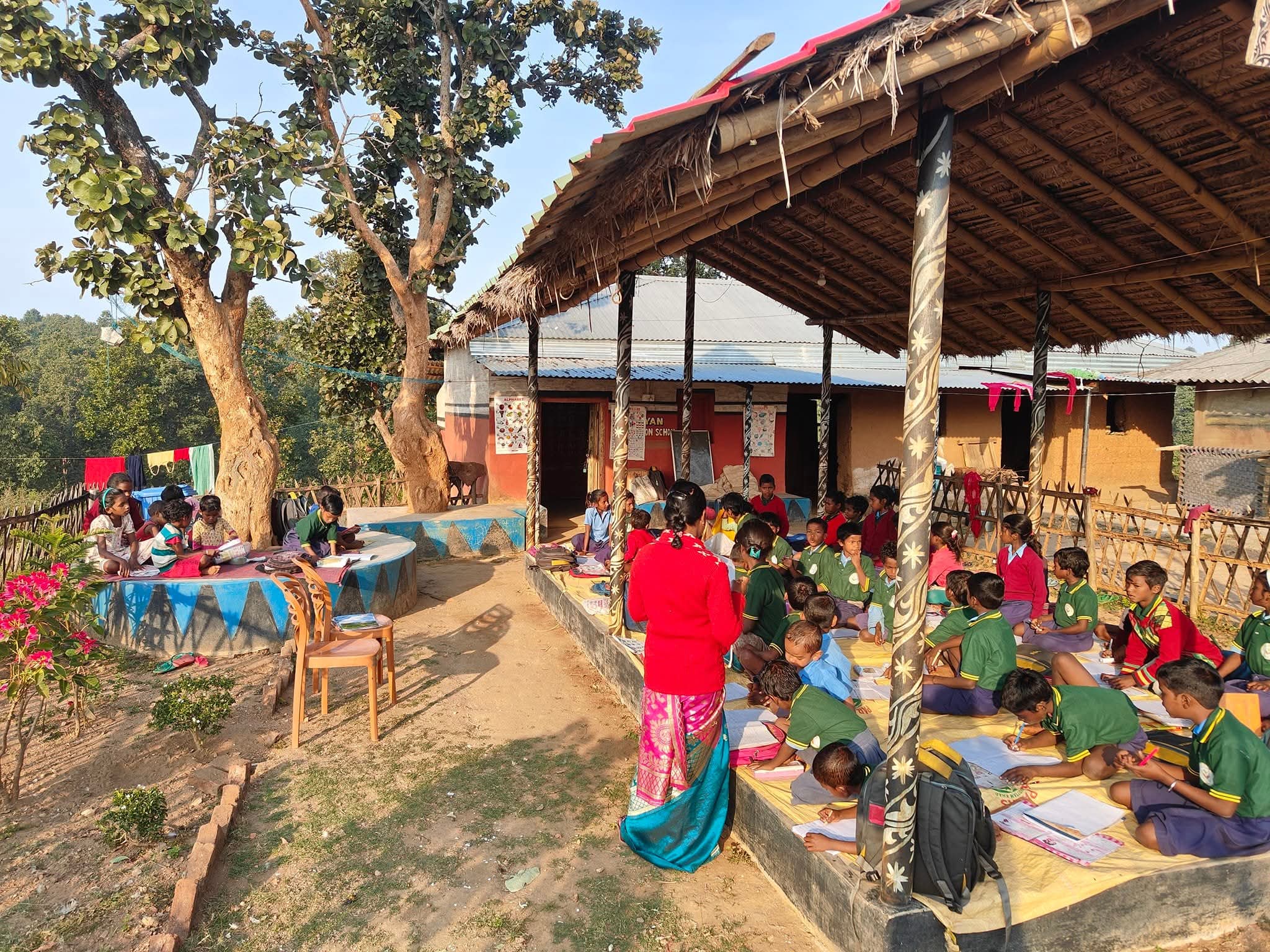 Children and teachers learning under a thatched pavilion in outdoor classroom setting