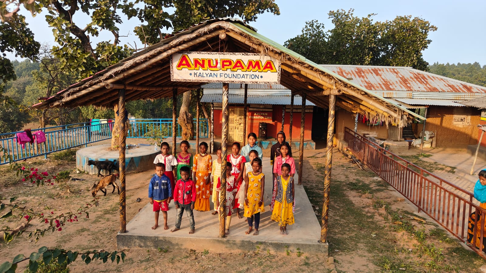 Children and teachers posing in front of the Anupama Kalyan Foundation school entrance