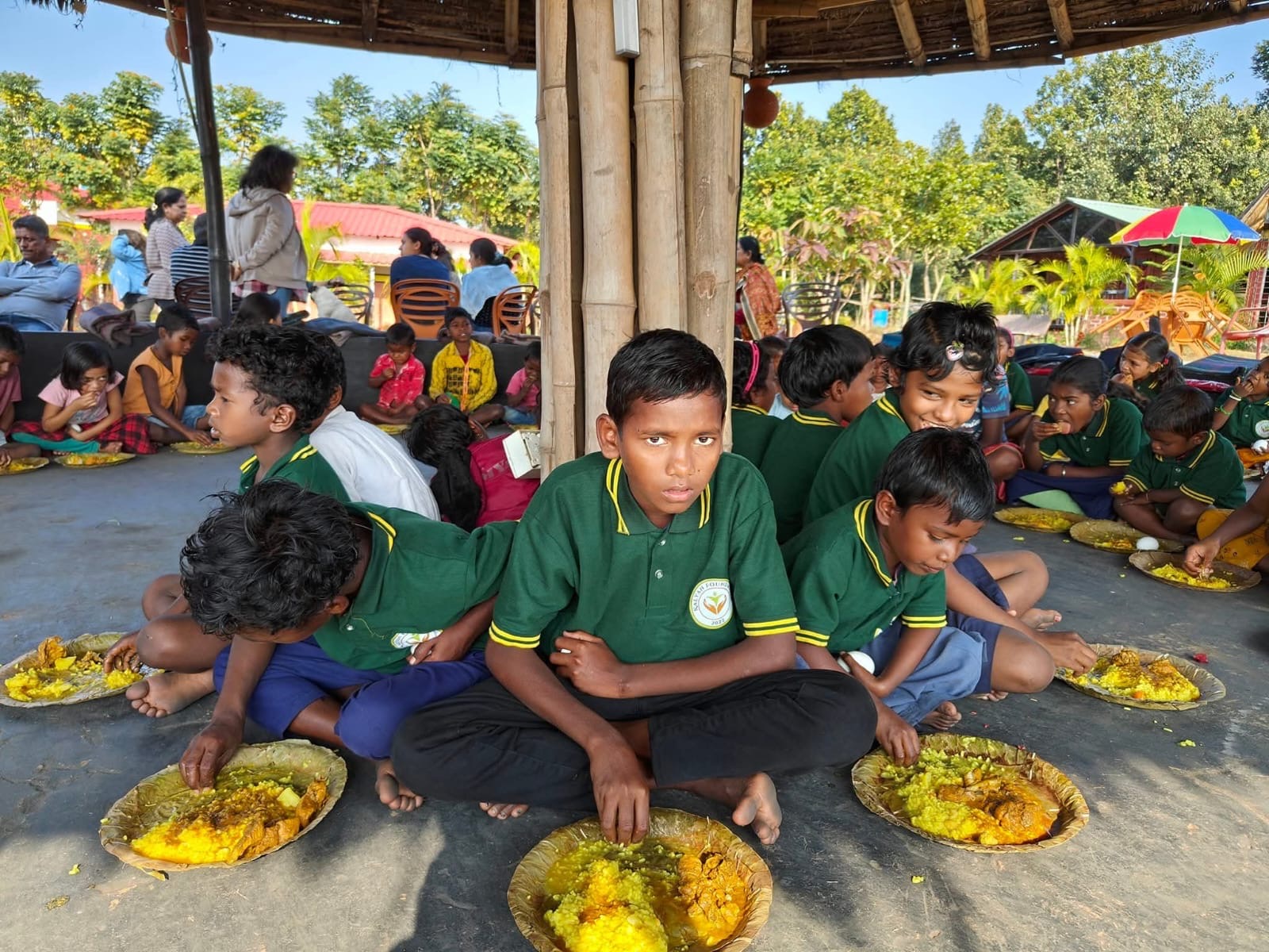 Children enjoying a community meal together under a covered structure