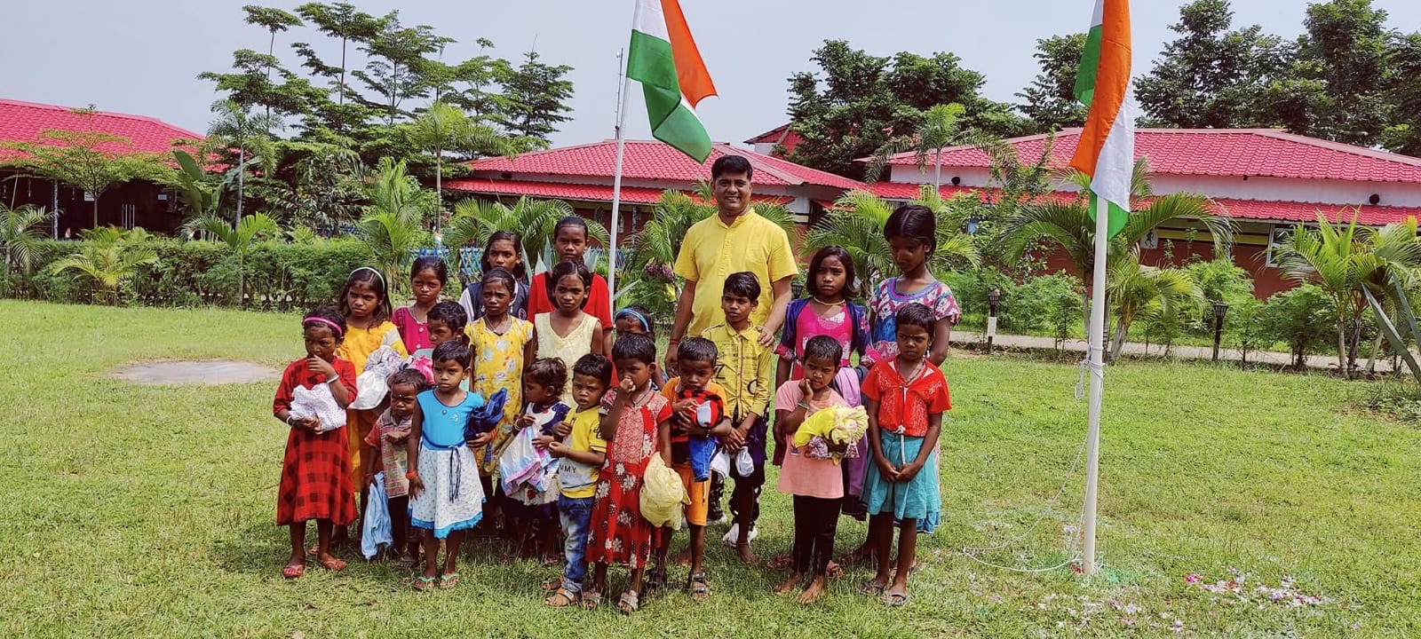 Large group of children and adults together on the school grounds with Indian flags